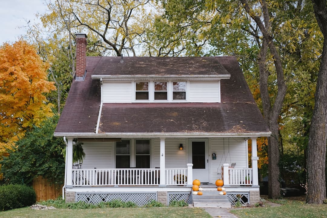 "A closed residential front door framed by a quiet suburban porch in soft daylight."