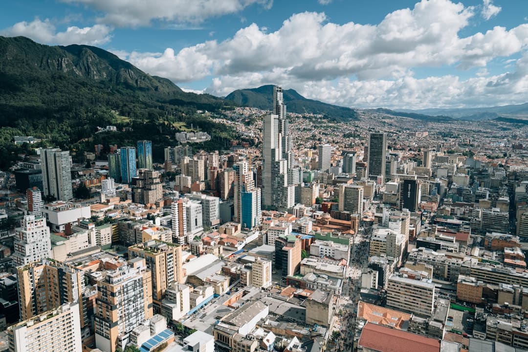 "Bogota cityscape with high-rise buildings backed by the Andes mountains under cloudy sky."